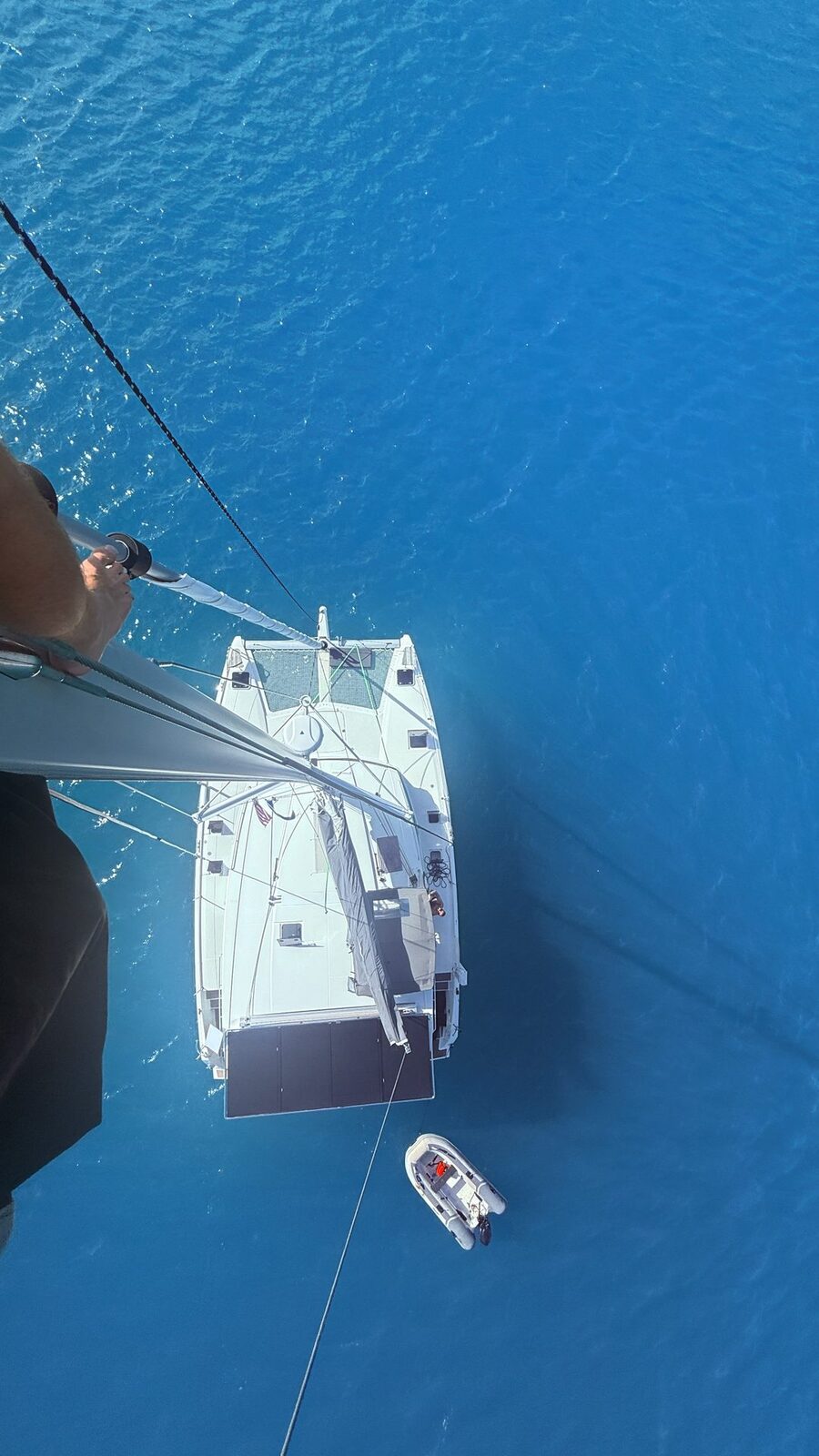 Aerial view of a private catamaran charter towing its dinghy through the Exumas